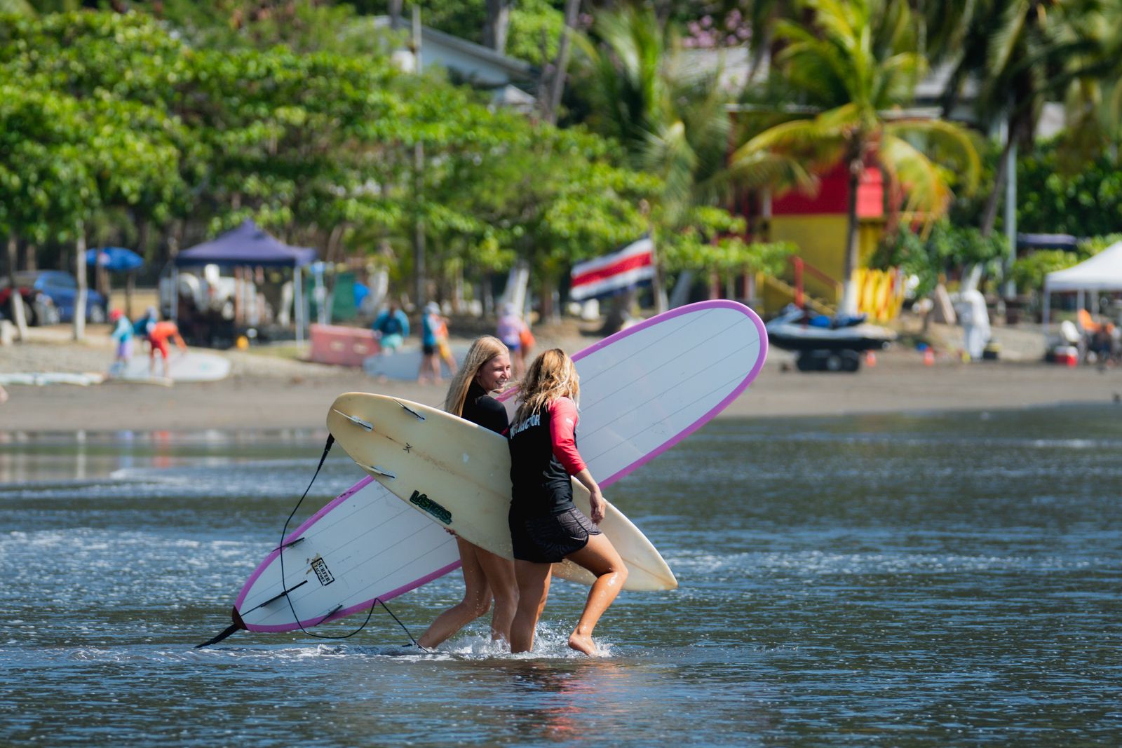 Two students carrying longboards into the water