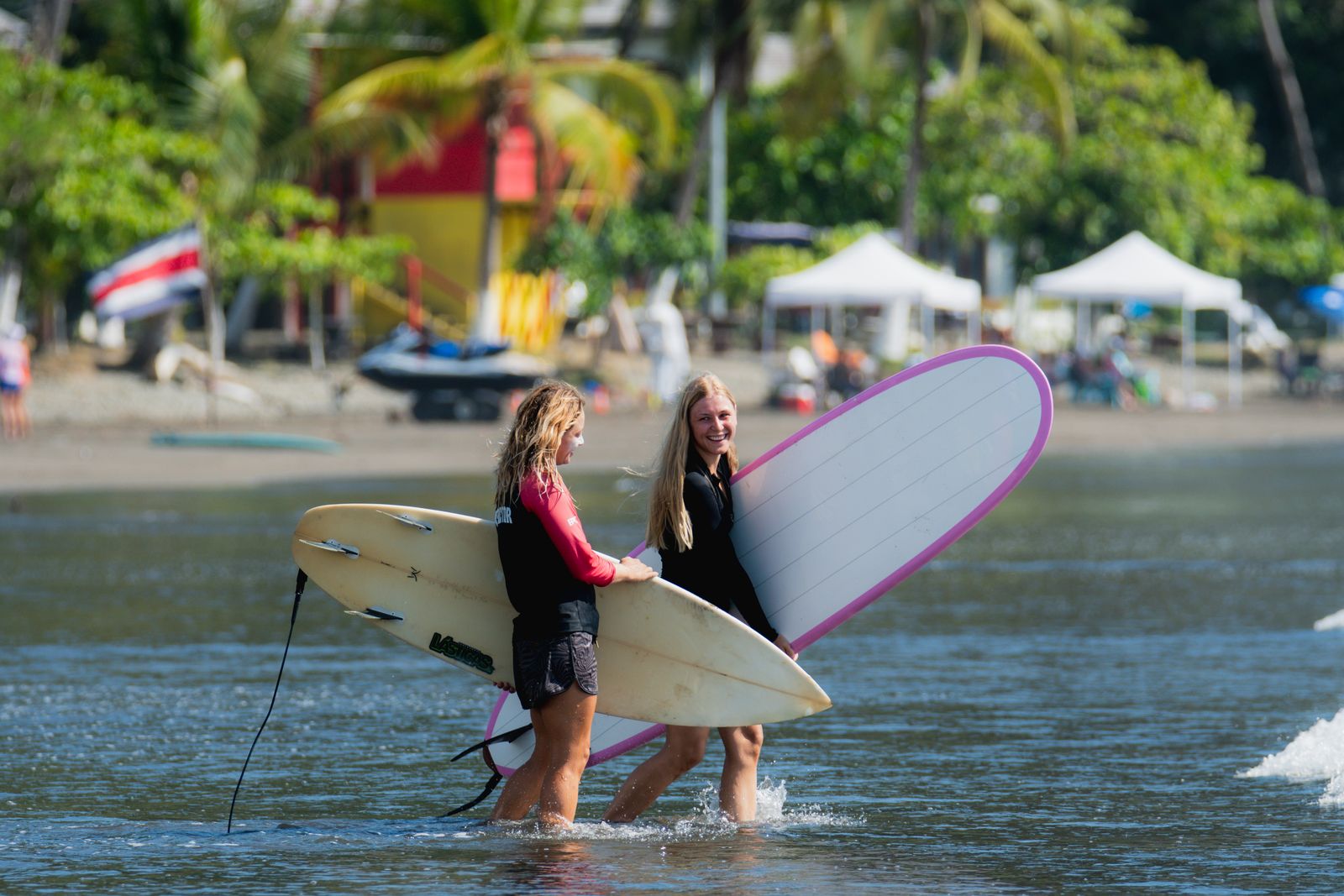 Two surfers walking into the water with their boards