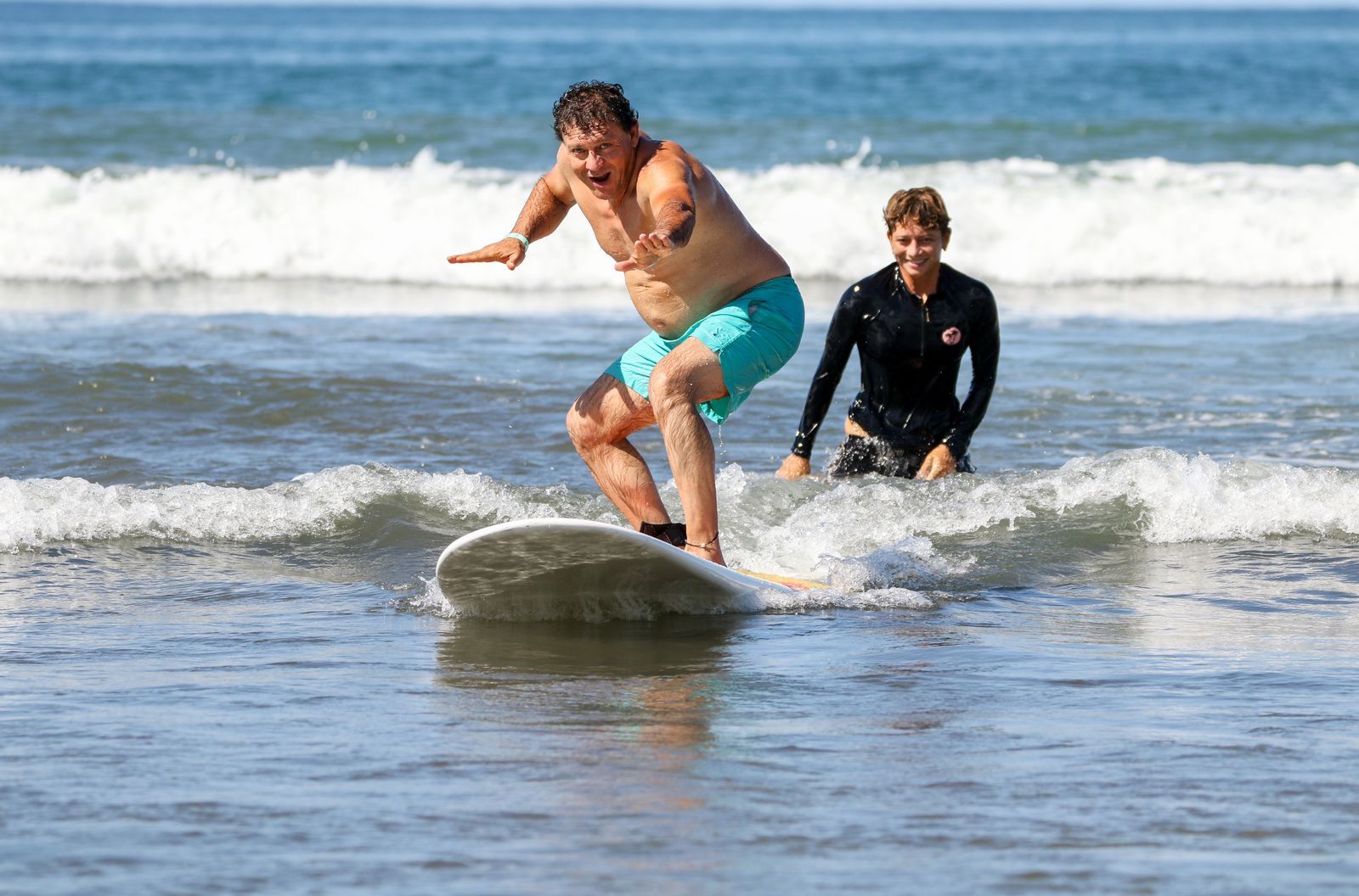 A student standing up on a wave during a surf lesson at Jacó Beach