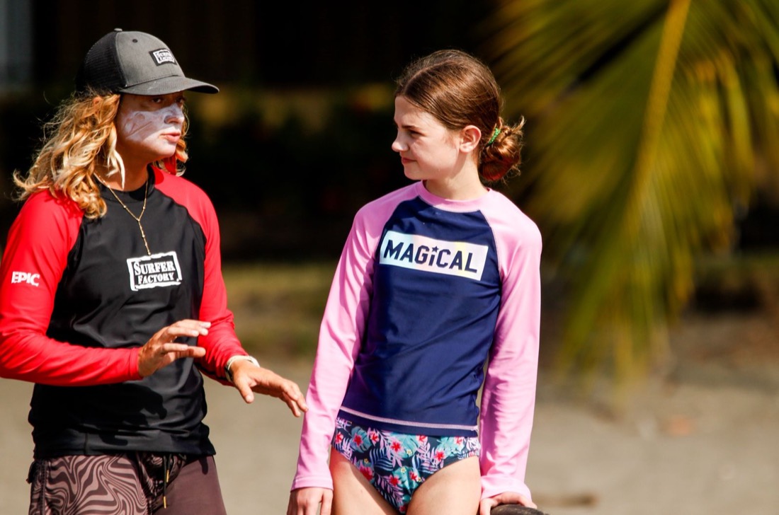 María coaching a young surfer on the beach in Jacó
